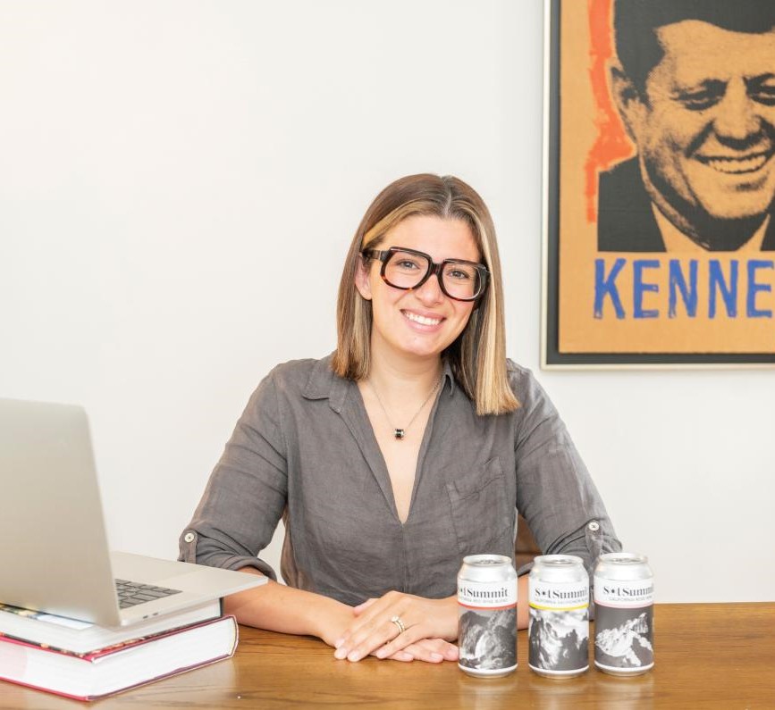 woman sitting at desk with three cans on desk